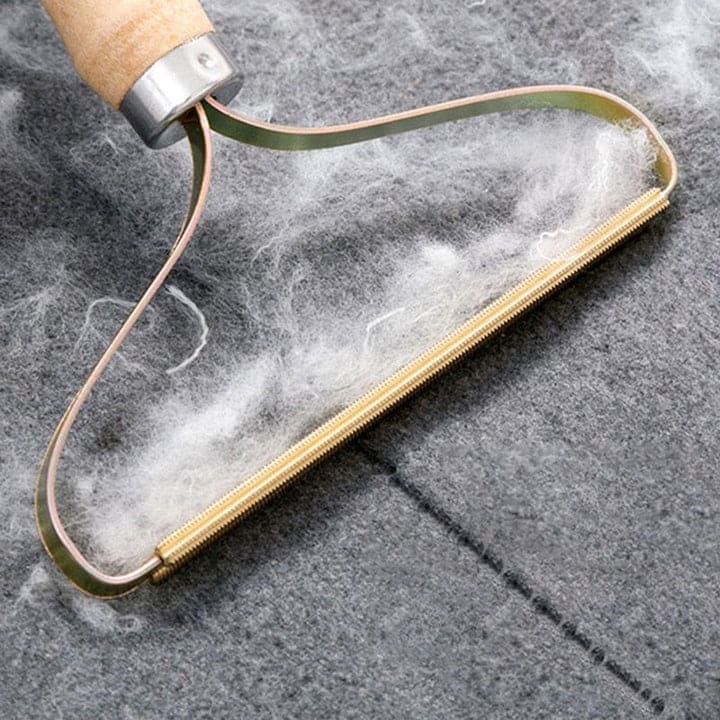 Hand using lint remover to clean sweater and restore smooth fabric surface.