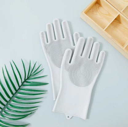 Pair of white scrubbing gloves on a light blue background with a wooden tray and green leaf.