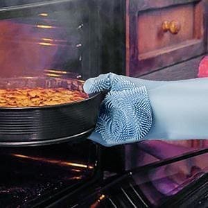 Person wearing a blue glove taking a pan out of an oven with food.
