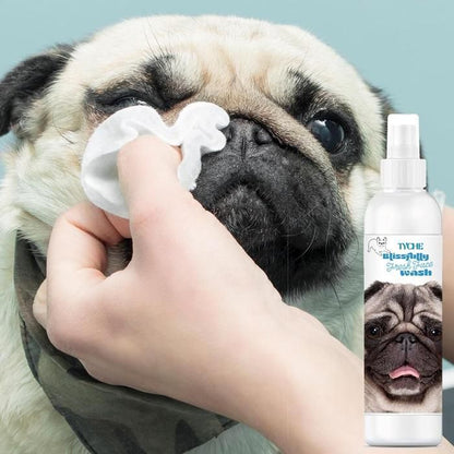 A pug dog having facewash applied to its face by a human hand, with a bottle of 'Tyche Blissfully Flat Facewash' shown beside the dog.
